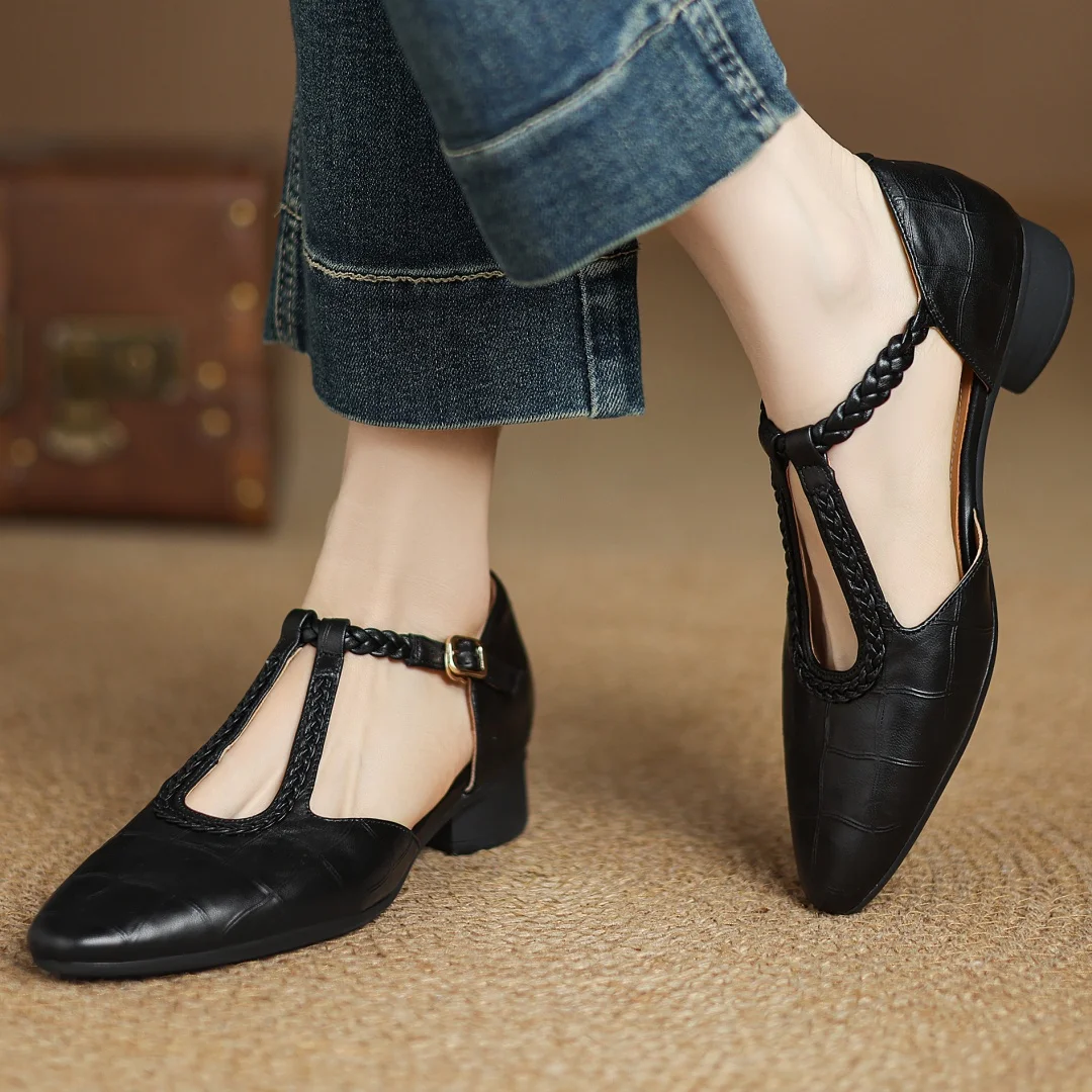 Women’s pointed toe flat with braided strap and buckle shown against a plain background.