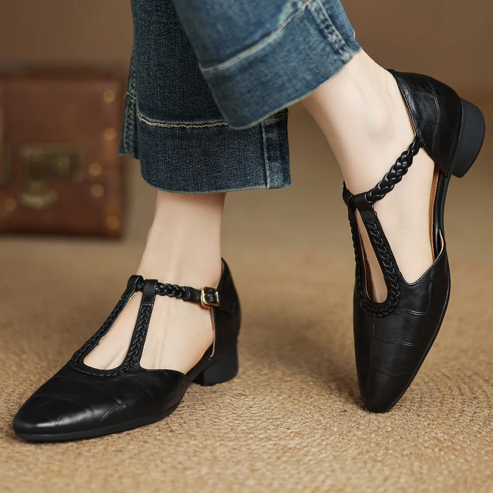 Women’s pointed toe flat with braided strap and buckle shown against a plain background.