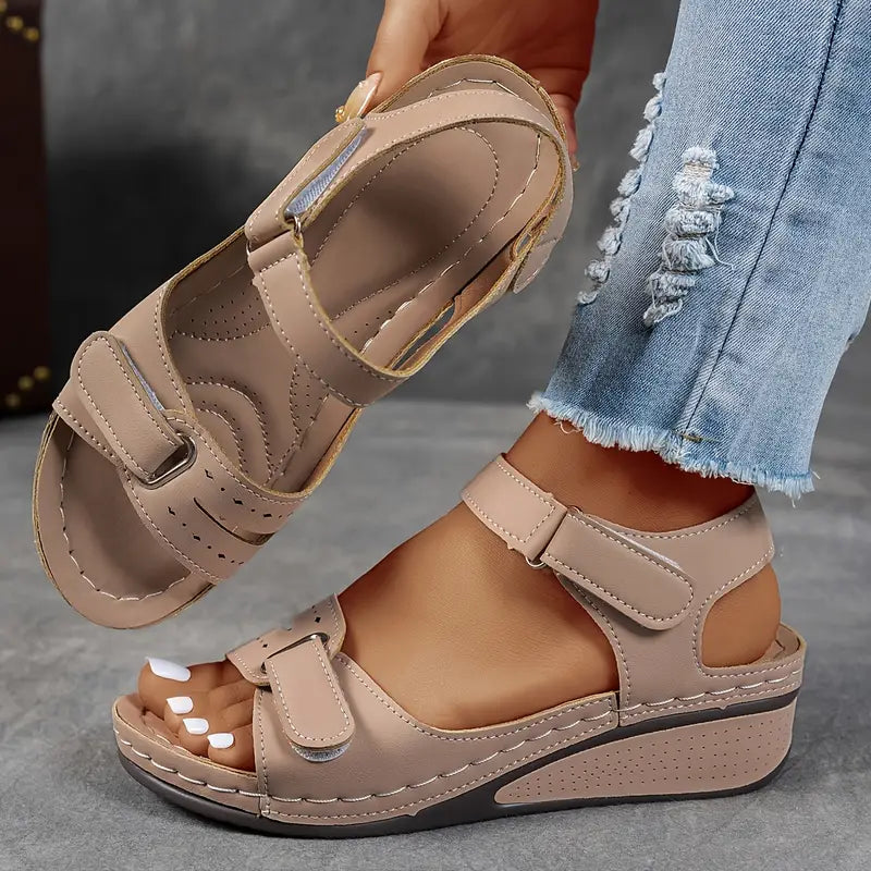 Female model displaying wedge heel sandals on a plain background.