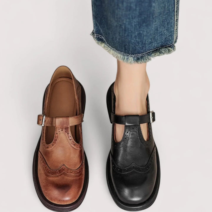Woman foot on styling black Mary Jane shoes on a plain background.
