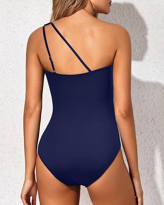 Female model in a beach ready one shoulder bathing suit against a plain background.