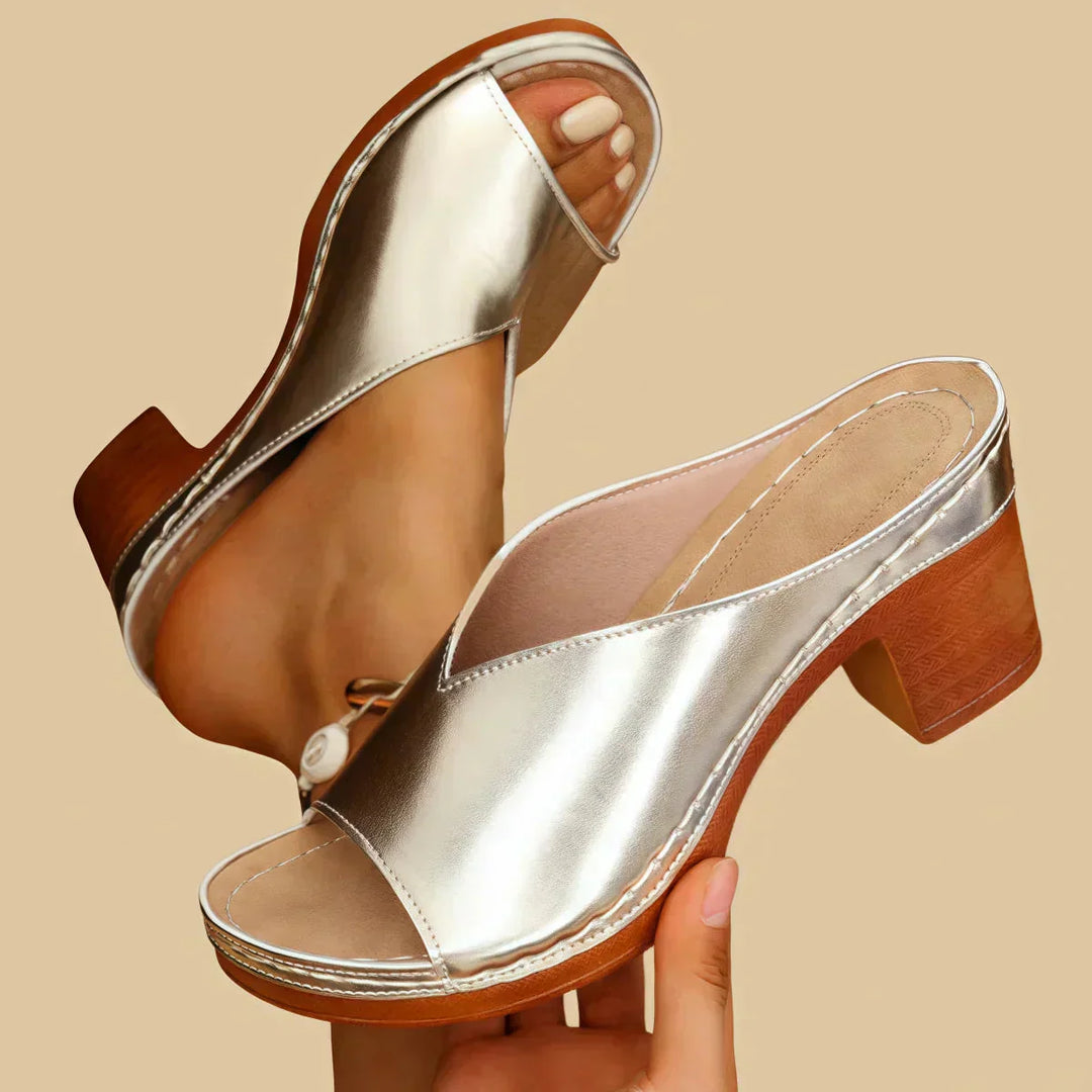 Woman showcasing slip-on summer sandals against a plain background.