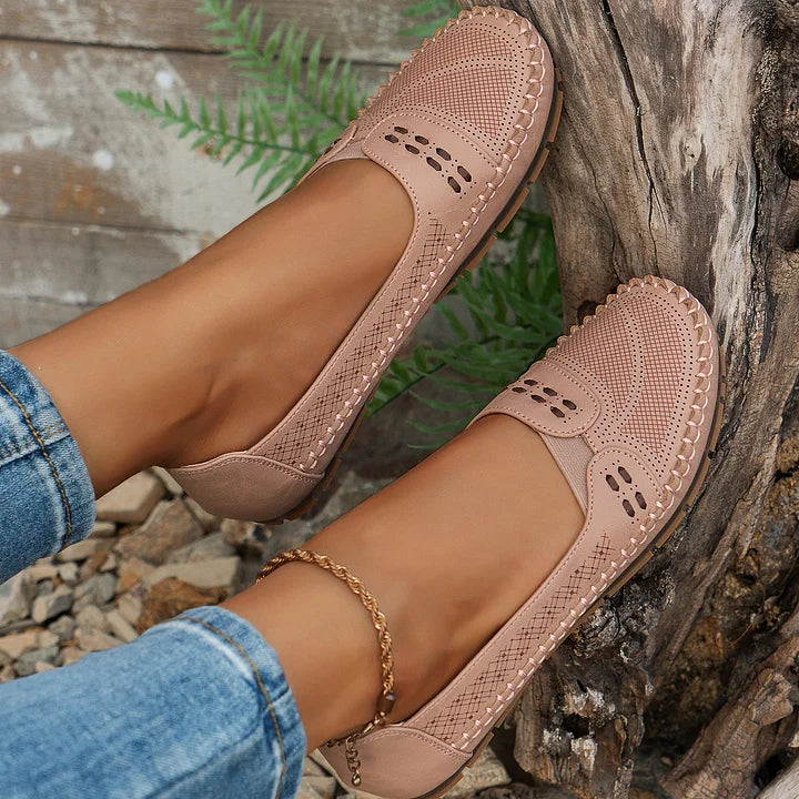 Female model showing walking flats on a nature background.