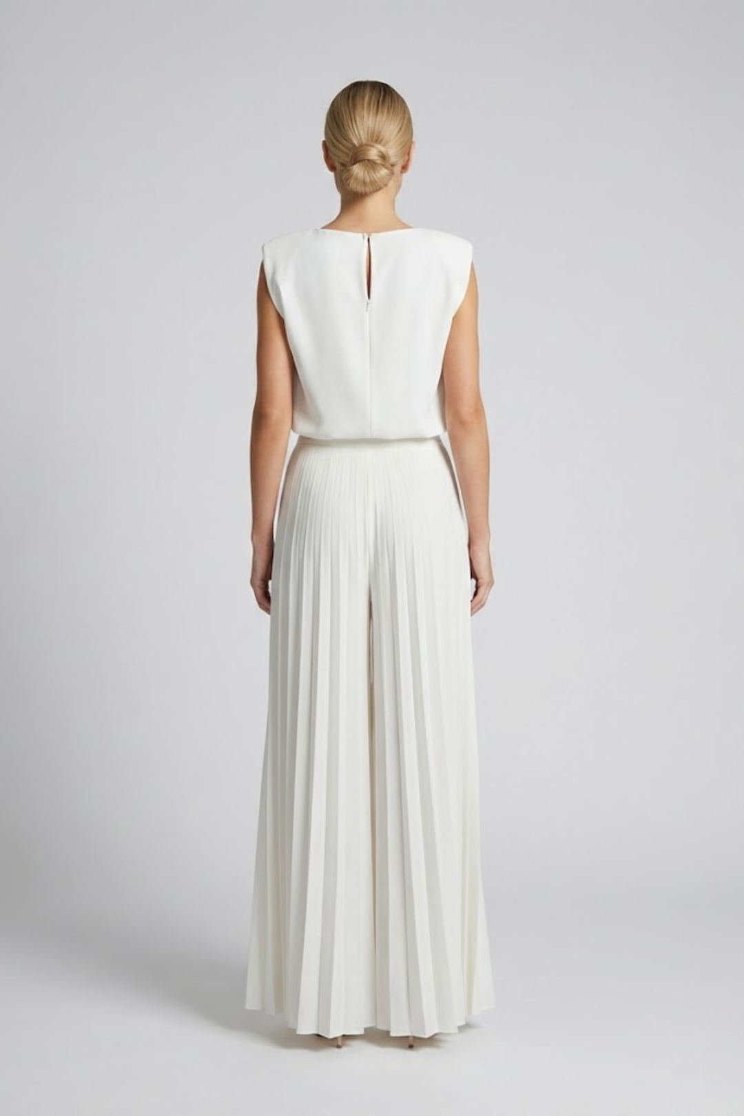 Woman wearing a sleeveless co-ord set with wide-leg trousers on a plain background.
