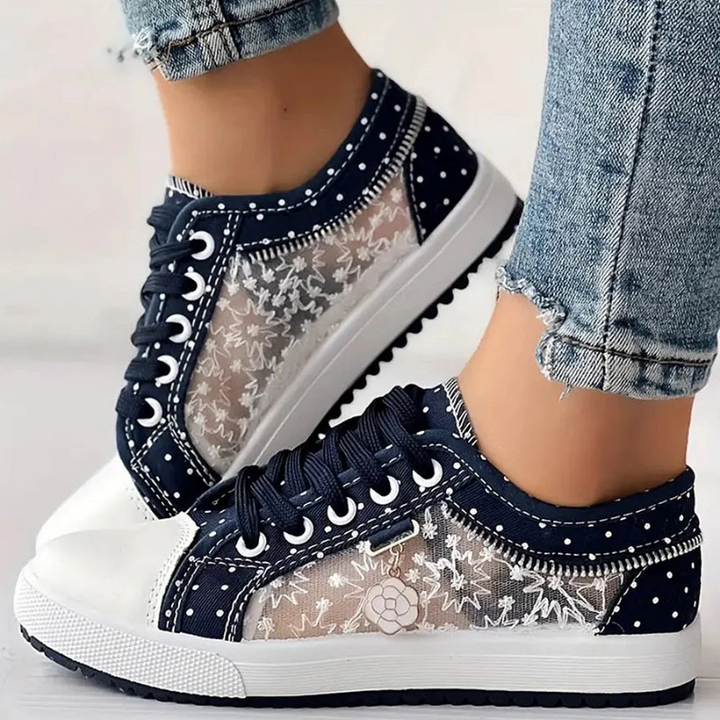 Female model in classic trainers with a supportive sole on a plain background.