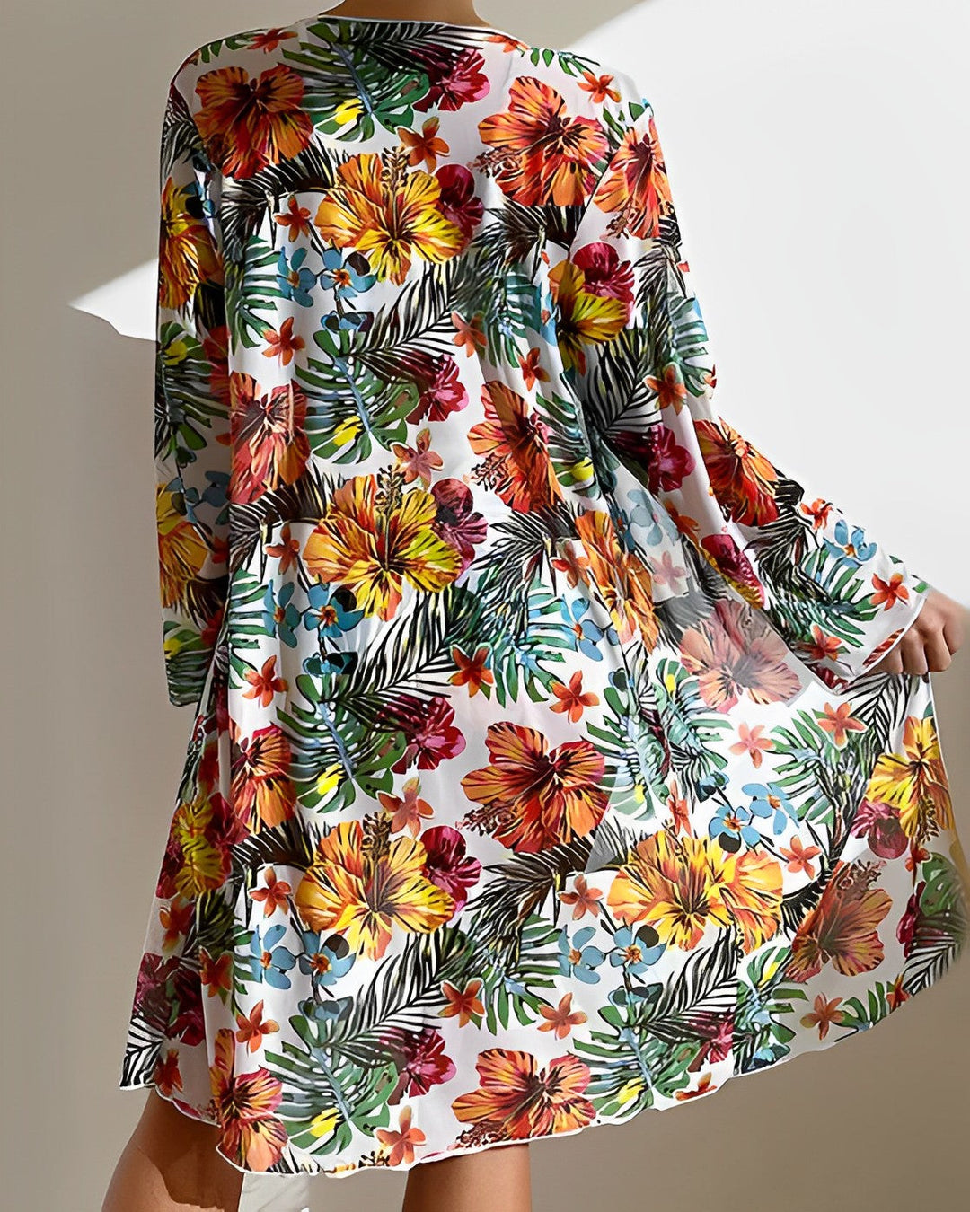 Model in a tropical print bikini set with matching skirt cover-up on a plain background.