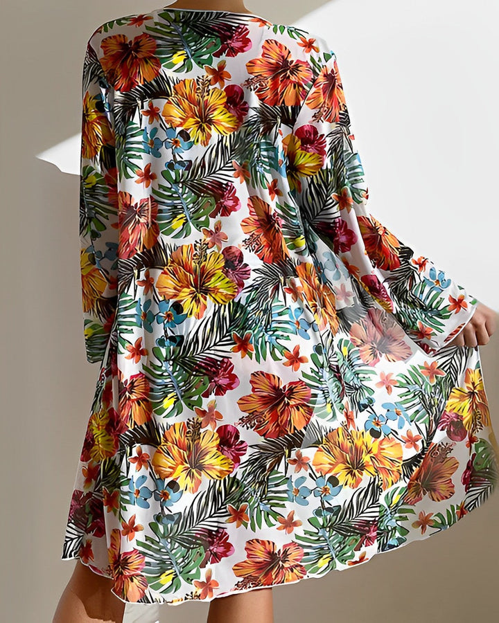 Model in a tropical print bikini set with matching skirt cover-up on a plain background.