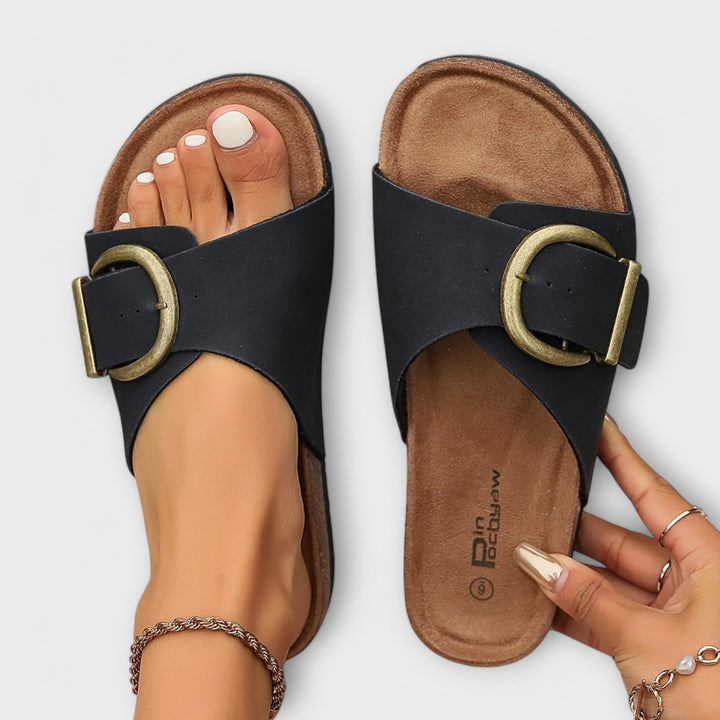 Female model wearing casual open-toe sandals on a plain background.