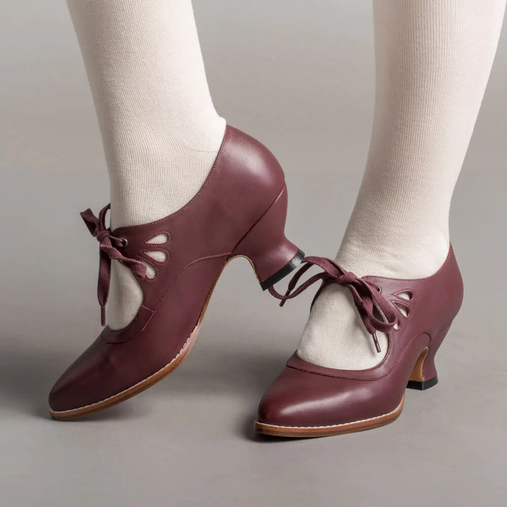 Woman showcasing classic mid-height heels with a plain background.