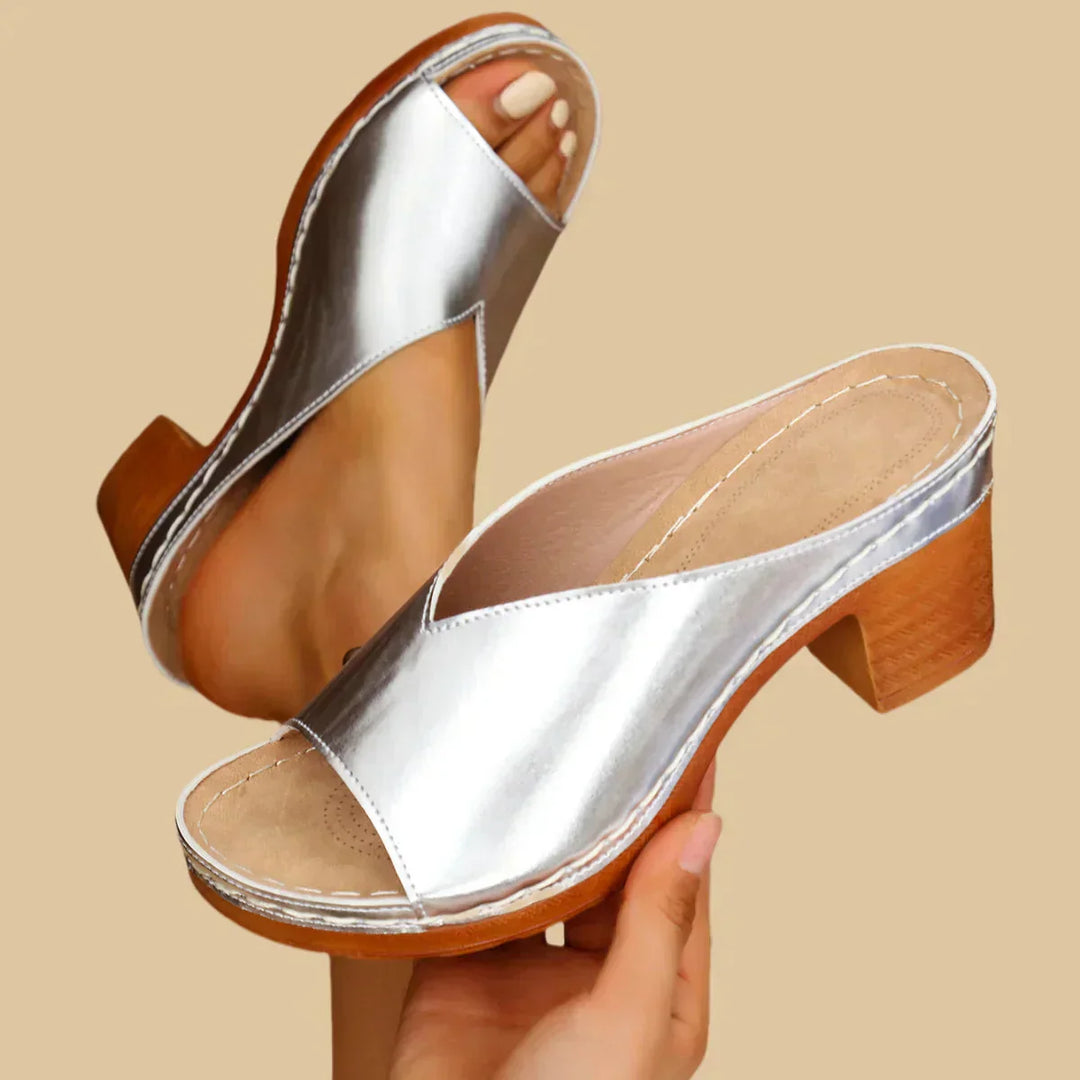 Woman standing in stylish heeled sandals on a plain background.