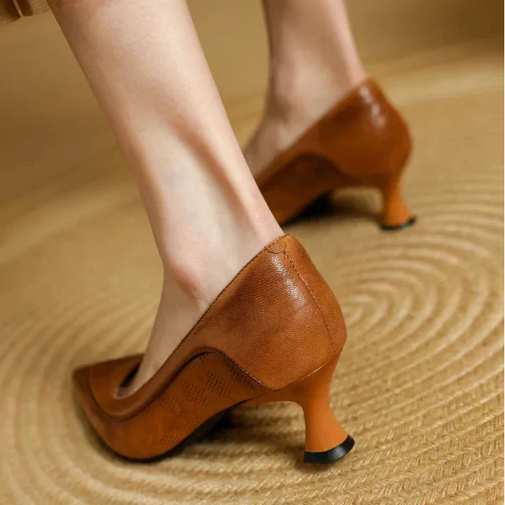 Woman styling pointed toe heels with a plain background.