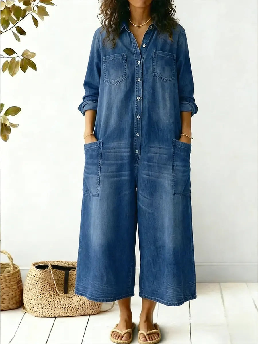 Female model in a roomy wide-leg denim jumpsuit shown on a plain background.
