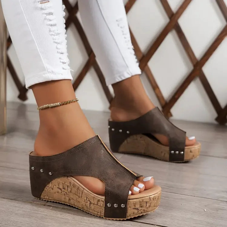 Woman displaying casual everyday sandals on a plain background.