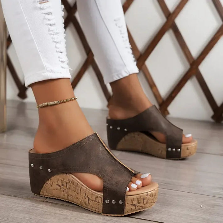 Woman displaying casual everyday sandals on a plain background.
