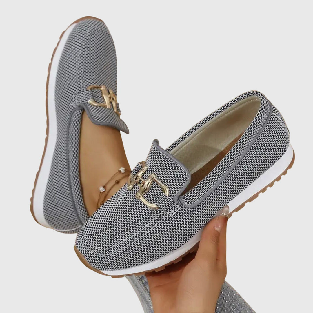 Woman showing refined casual shoes on a plain background.