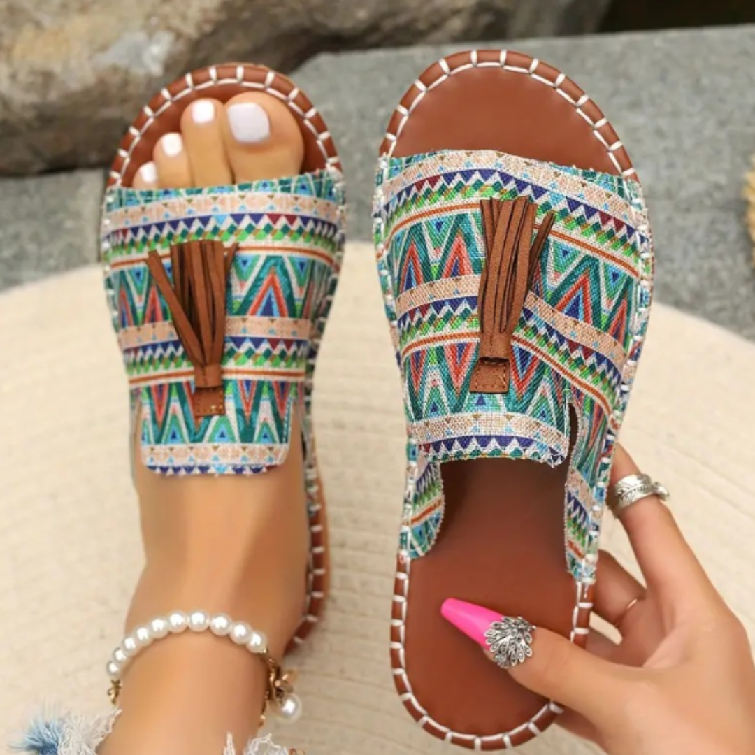 Woman posing in open-toe sandals with a plain background.