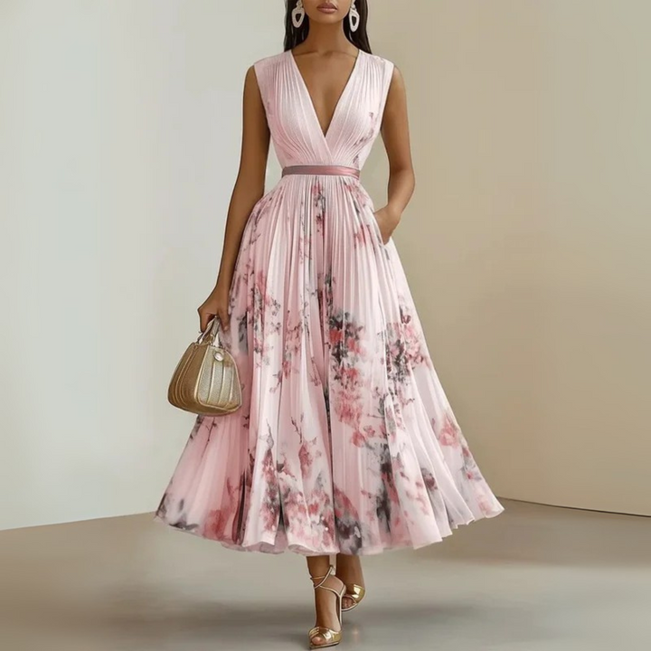 Woman in a sleeveless maxi dress featuring a pleated skirt and defined waist seam.