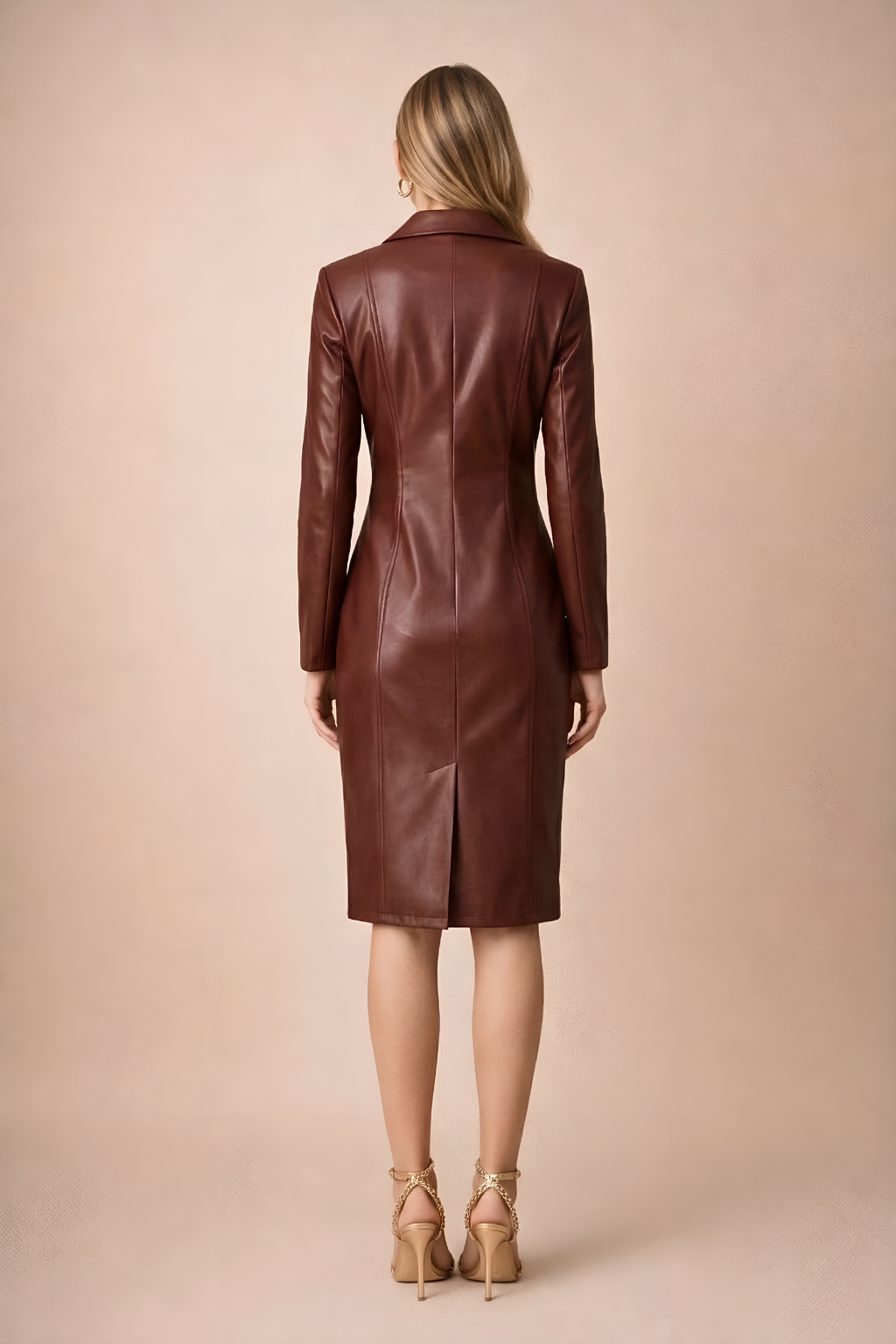 Female model showcasing a structured faux leather blazer dress with a sleek midi silhouette on a plain background.
