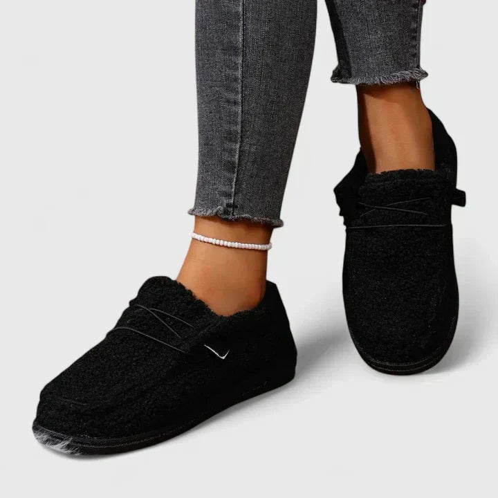 Female model wearing everyday slip-on shoes on a plain background.