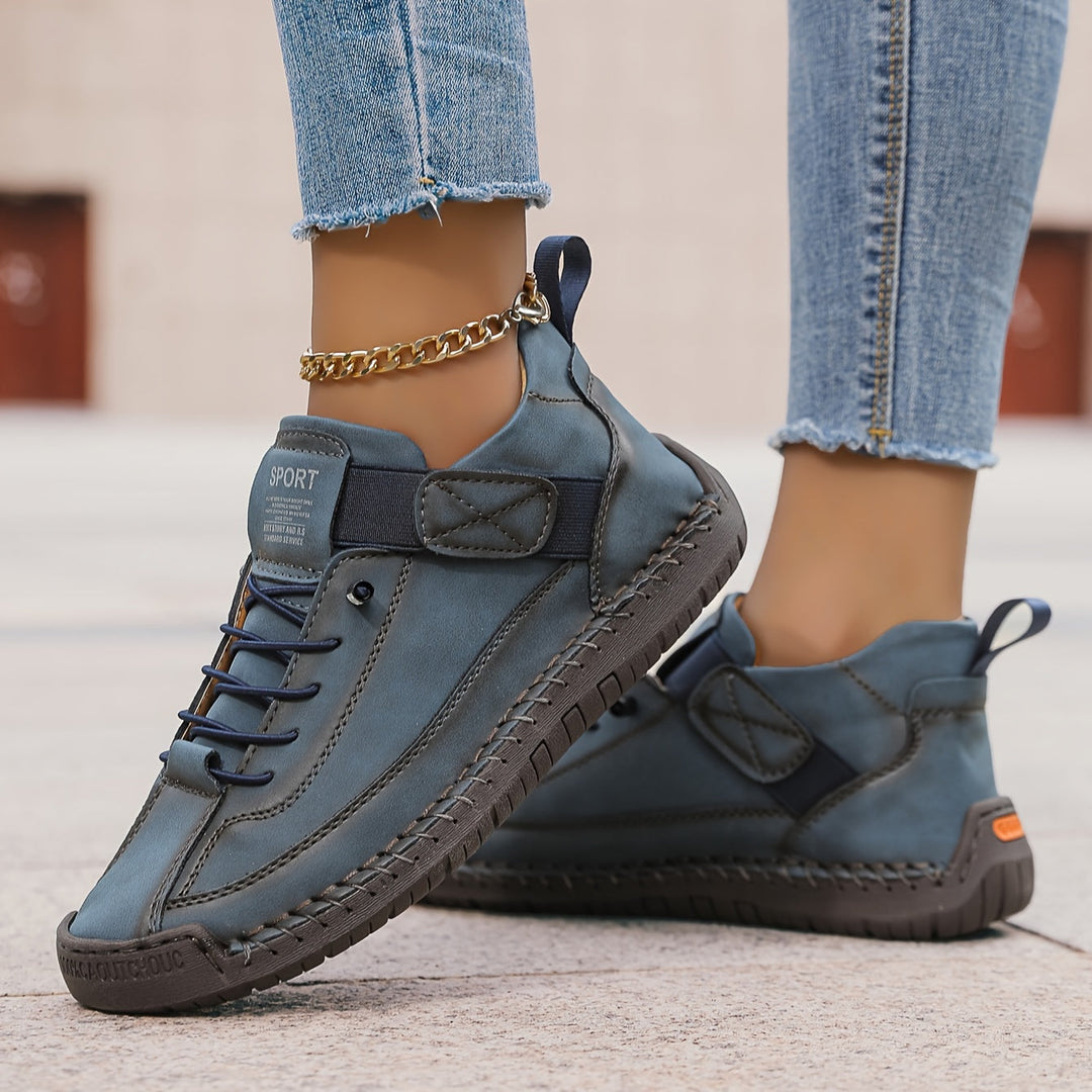 Woman showcasing versatile trainers suitable for everyday styling on a plain background.