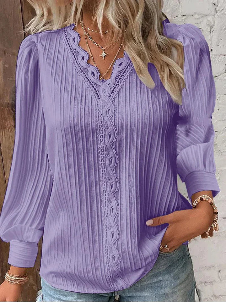  Female wearing a chiffon blouse with elegant lace accents on a plain background.