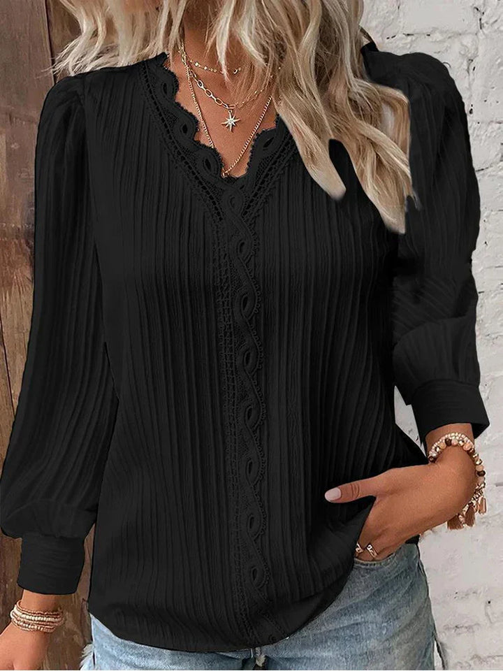Woman wearing a chiffon blouse with lace detail accents against a plain background.