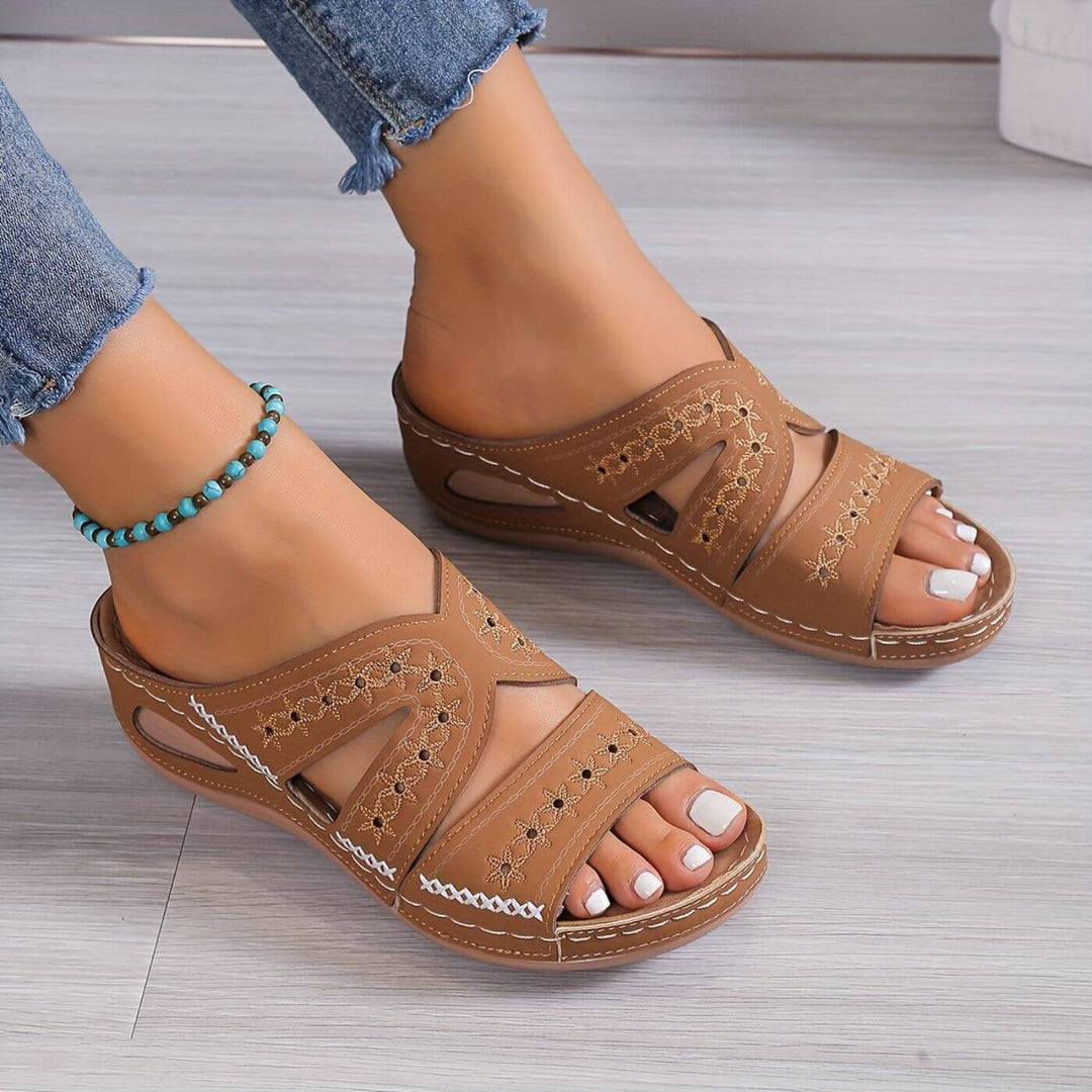 Female wearing supportive flat sandals on a plain background.