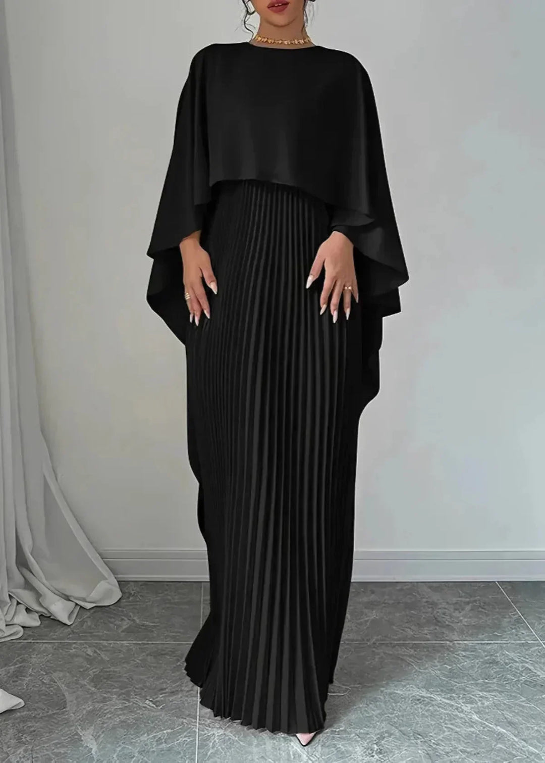 Female model in a long event dress with soft pleats on a plain background.