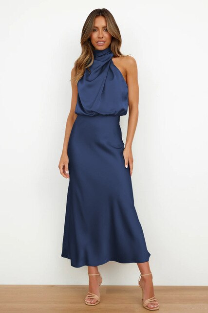 Woman standing in a body-hugging maxi gown against a plain background.