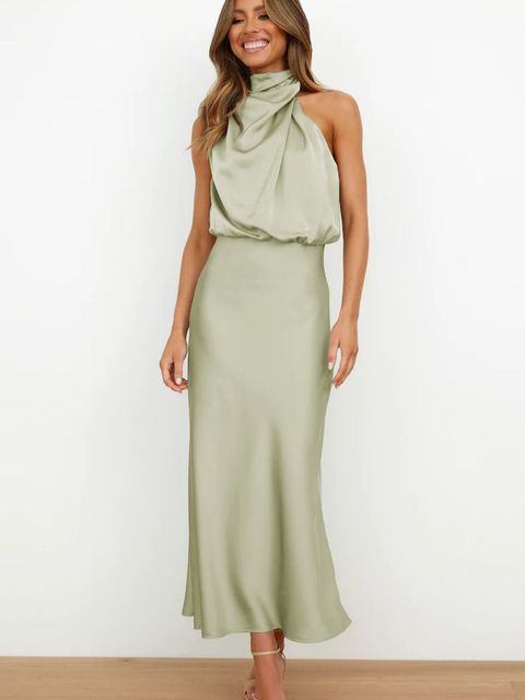 Female in a flowing evening outfit with an off-shoulder neckline on a plain background