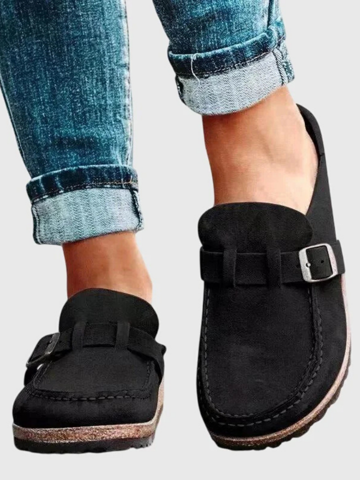 Female model wearing everyday comfort clogs on a plain background.