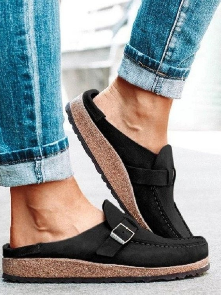 Female model showing soft footbed clogs on a plain background.