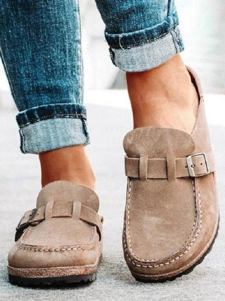 Woman showing cushioned slip-on clogs with relaxed casual wear on a plain background.