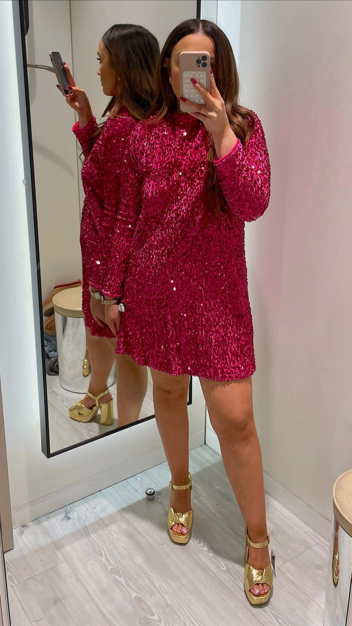 Woman in a fitted sequin cocktail dress with round neckline on a plain background.