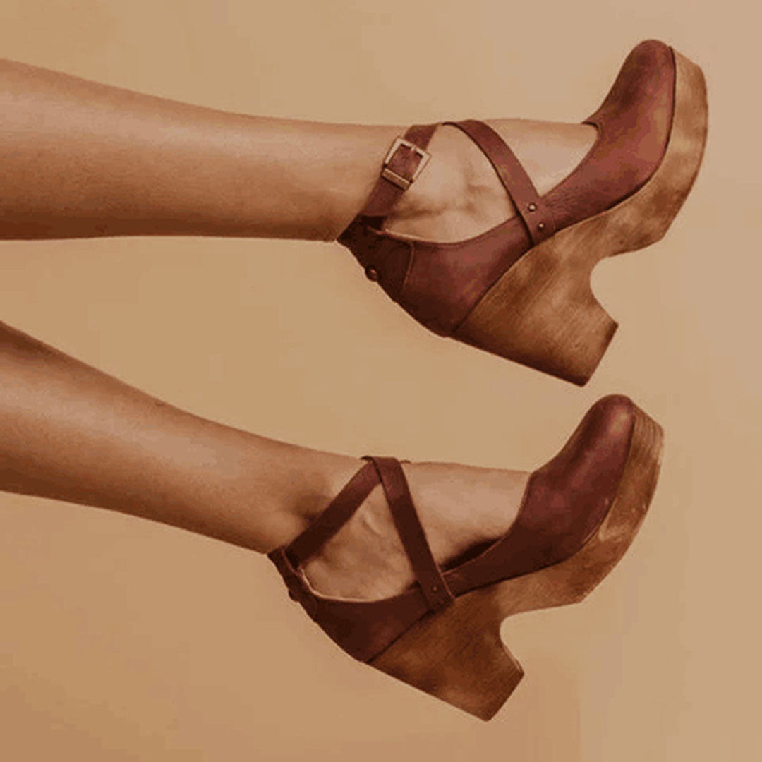 Female standing in stylish wedge heels with a closed toe design on a plain background.