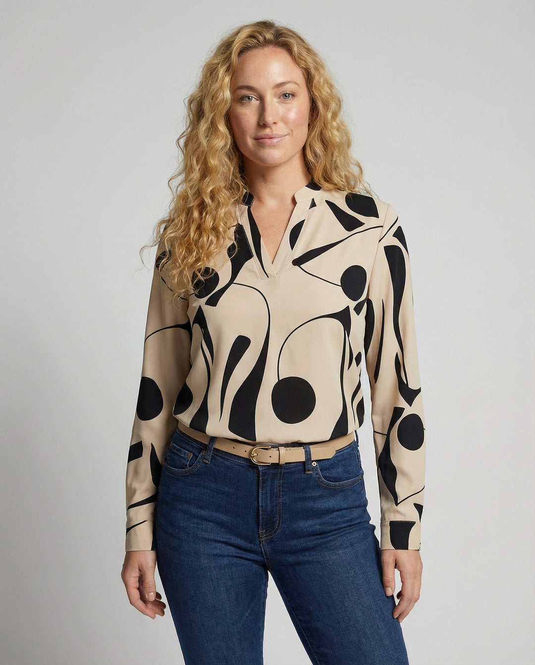 Woman wearing a long sleeve blouse against a plain background.