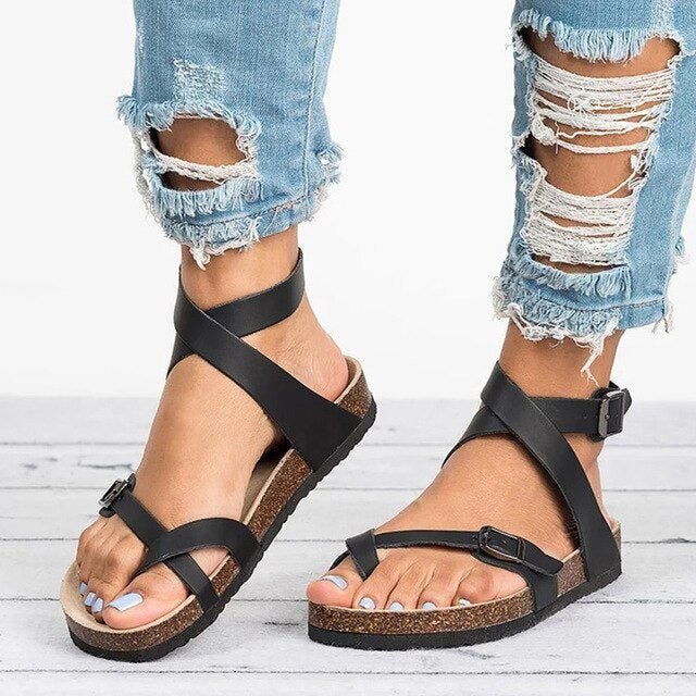 Female model standing in open-toe sandals with adjustable straps on a plain background.