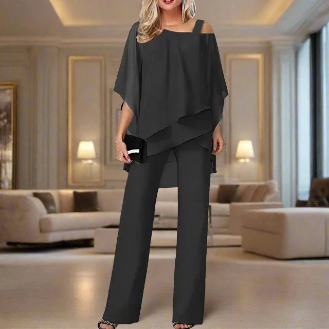 Woman modelling a chiffon top and trousers set on a plain background.