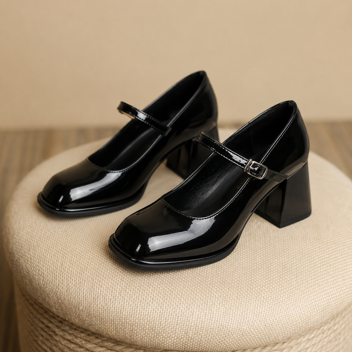 Patent-look ankle strap heels on a plain background.