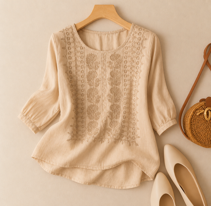 A relaxed blouse featuring decorative embroidery on a plain background.