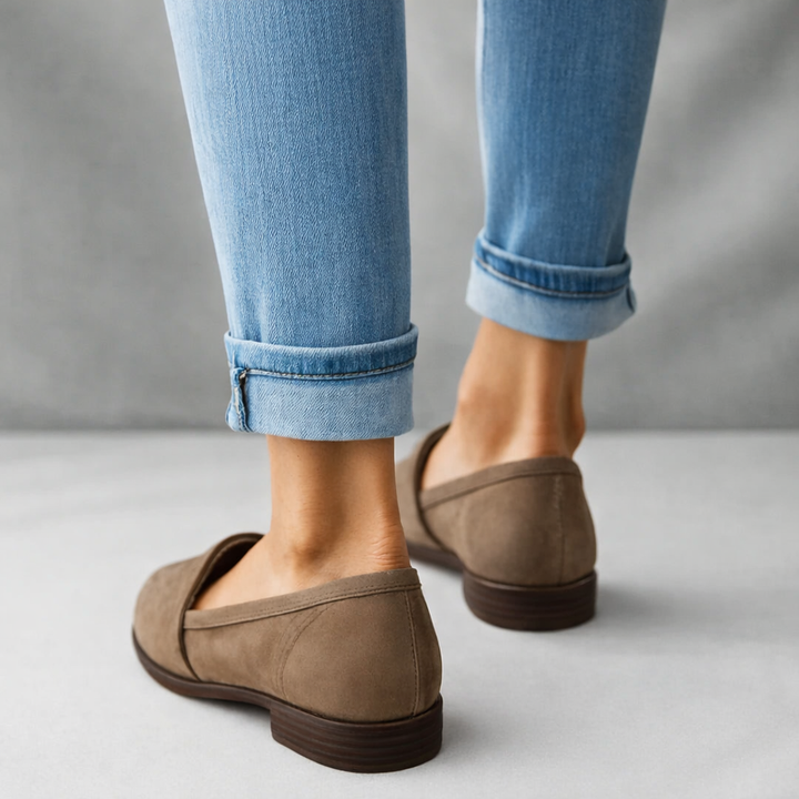 Woman standing in sleek low-profile loafers against a plain background.