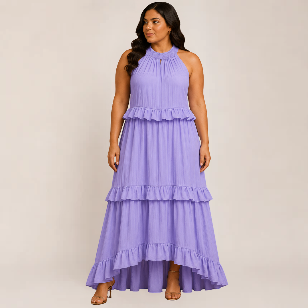 Woman in a flowing spaghetti strap maxi dress against a plain background.