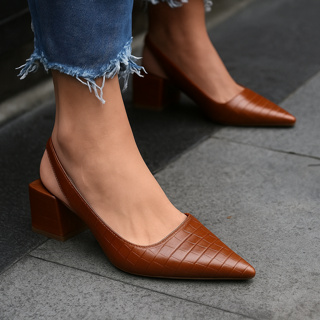 Female model showcasing stylish heels on a plain background.