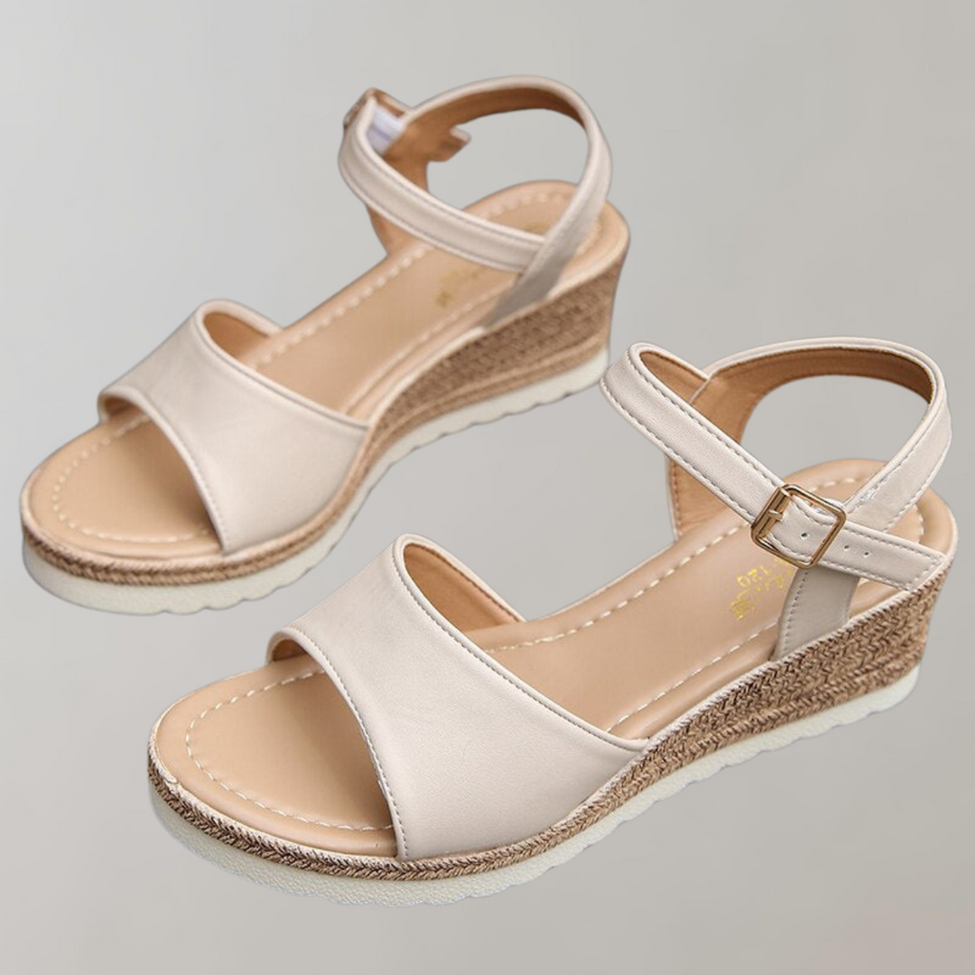 Female model showcasing comfortable wedge sandals with soft footbed on a plain background.