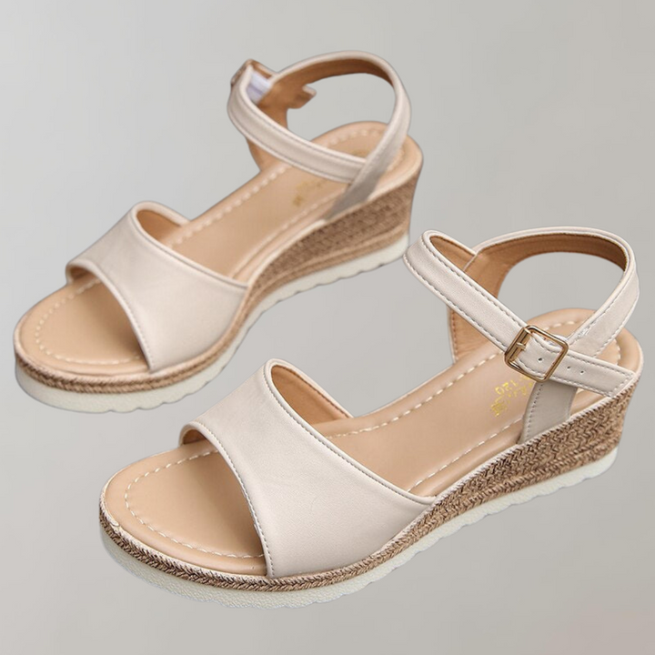 Female model showcasing comfortable wedge sandals with soft footbed on a plain background.