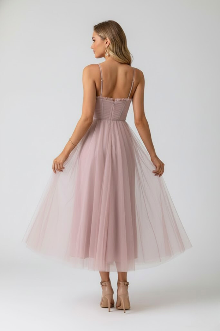 Woman styled in an occasion midi dress on a plain background.