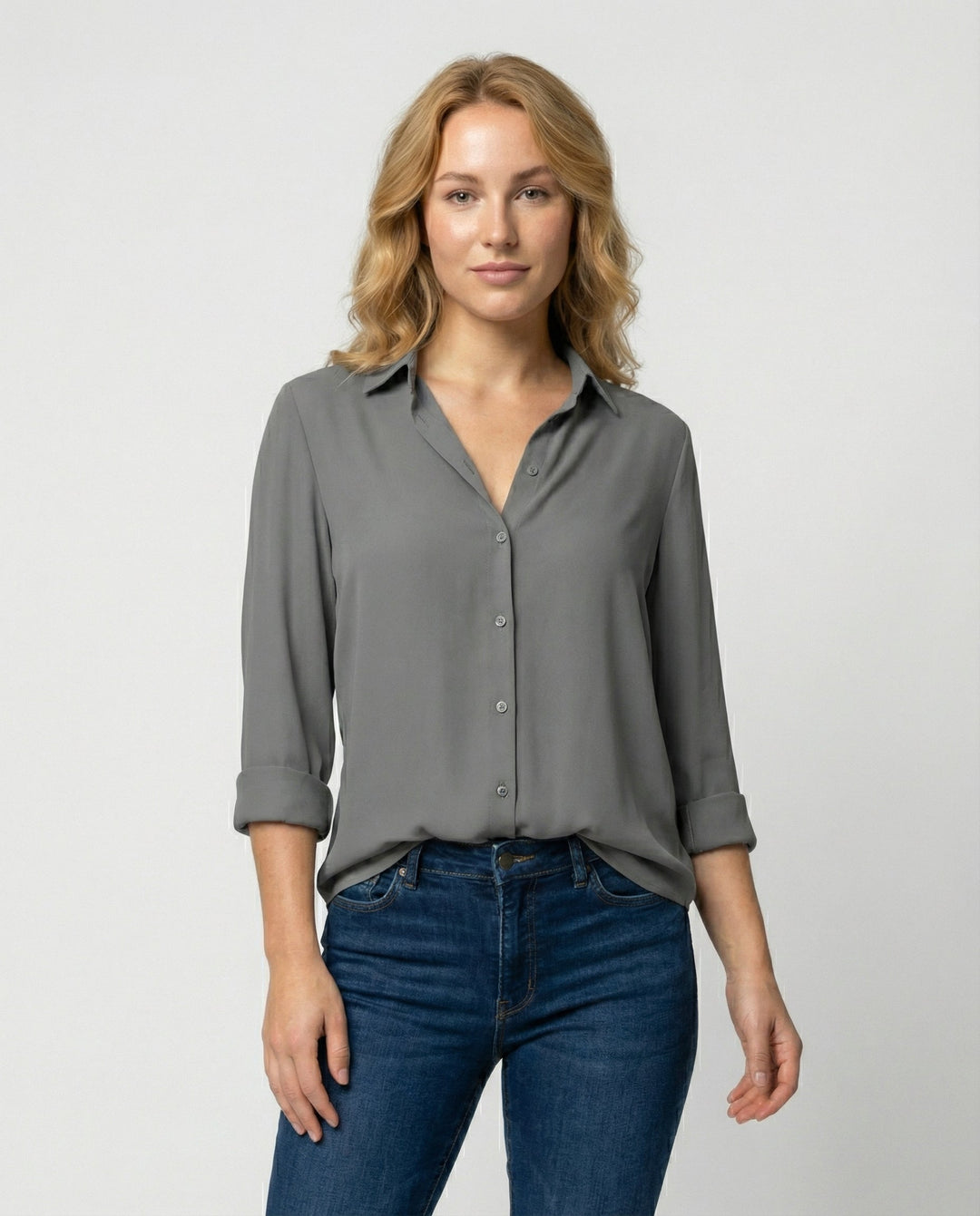 Woman wearing a long sleeve blouse with a classic collar against a plain background.