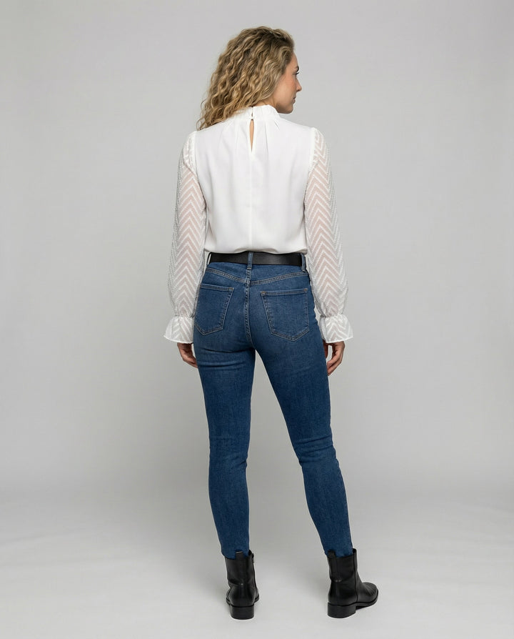 Woman in a stylish long-sleeved top with a feminine silhouette.