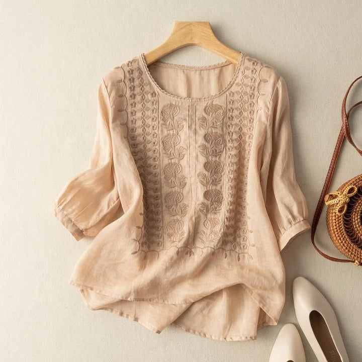 An embroidered blouse with cuffed sleeves against a plain background.