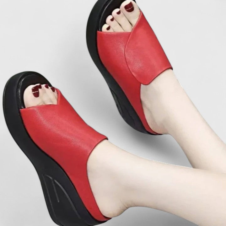 Woman showing side view of casual wedge sandals on a plain background.